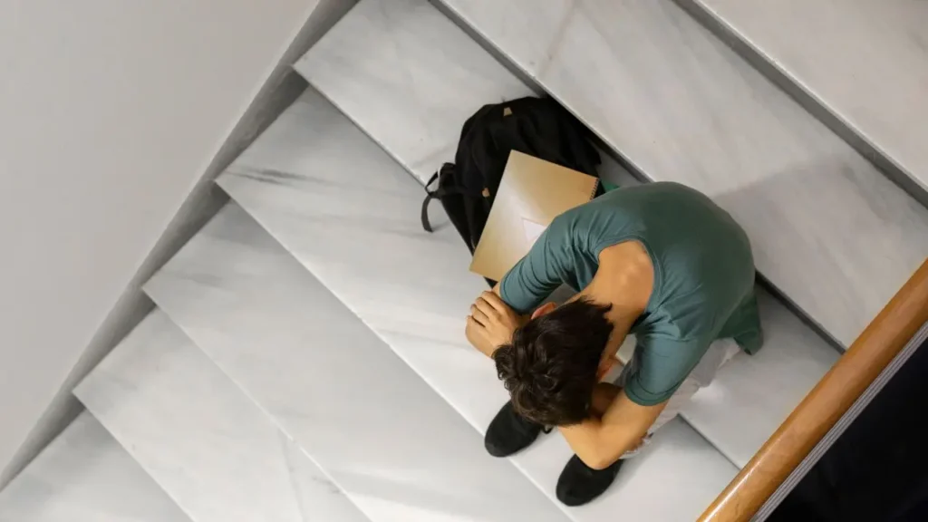 Vista de un joven en una escalera que se ha quedado sin vivienda al no contar con un seguro antiocupación
