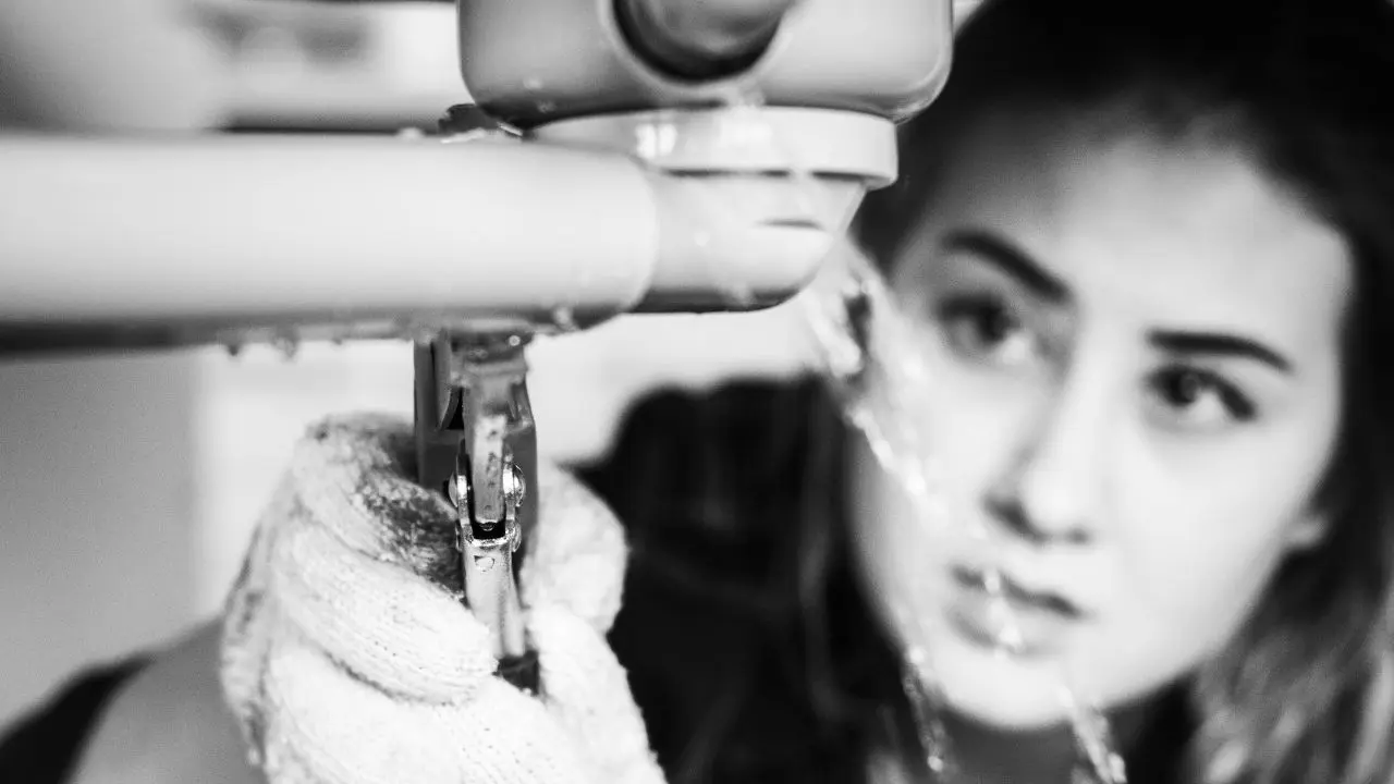 Una mujer trata de reparar sin éxito una fuga de agua en su casa
